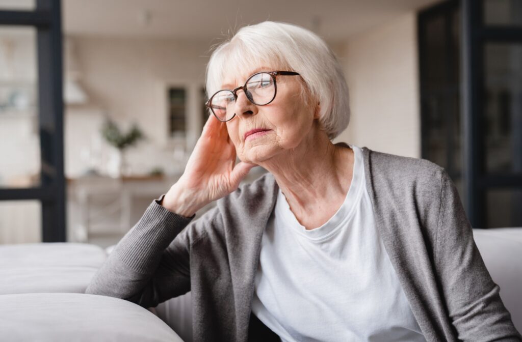 A senior looking out the window with a sad, contemplative expression.