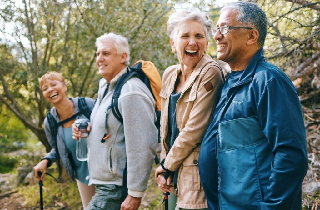 A group of happy senior friends talk and laugh while taking a hike near their independent living community.