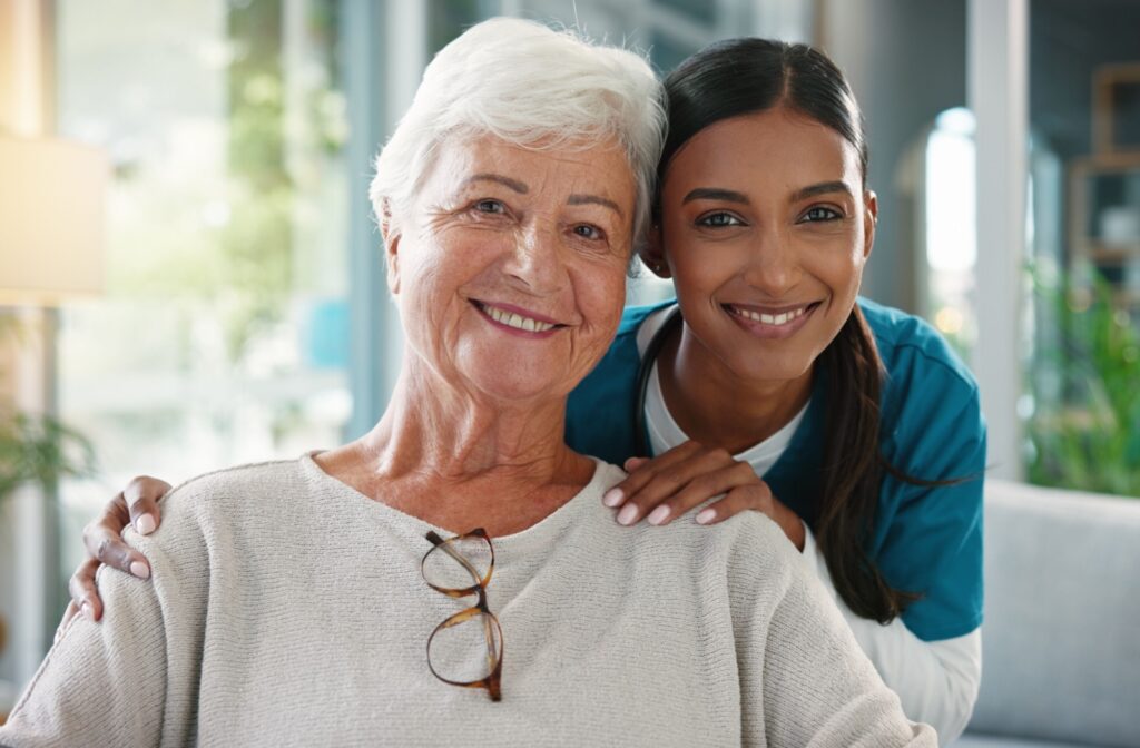 A caregiver and an older adult smile while sitting in a comfortable lounge in senior living