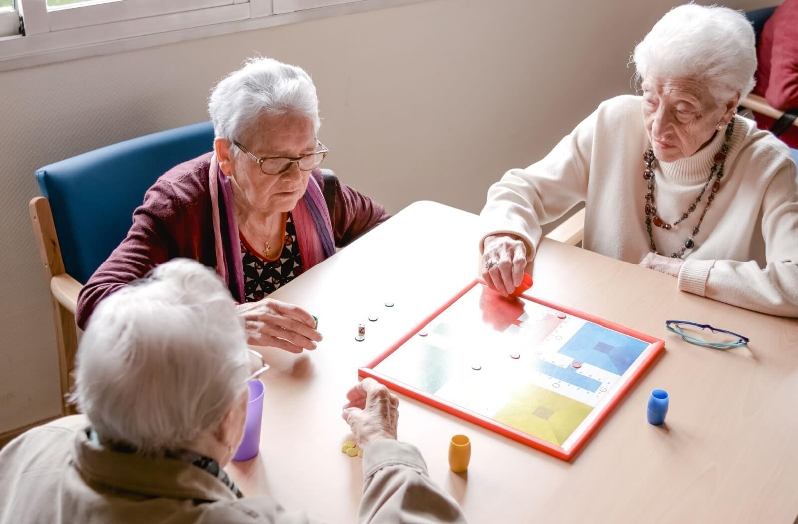 a group of 3 senior friends play a board game together.